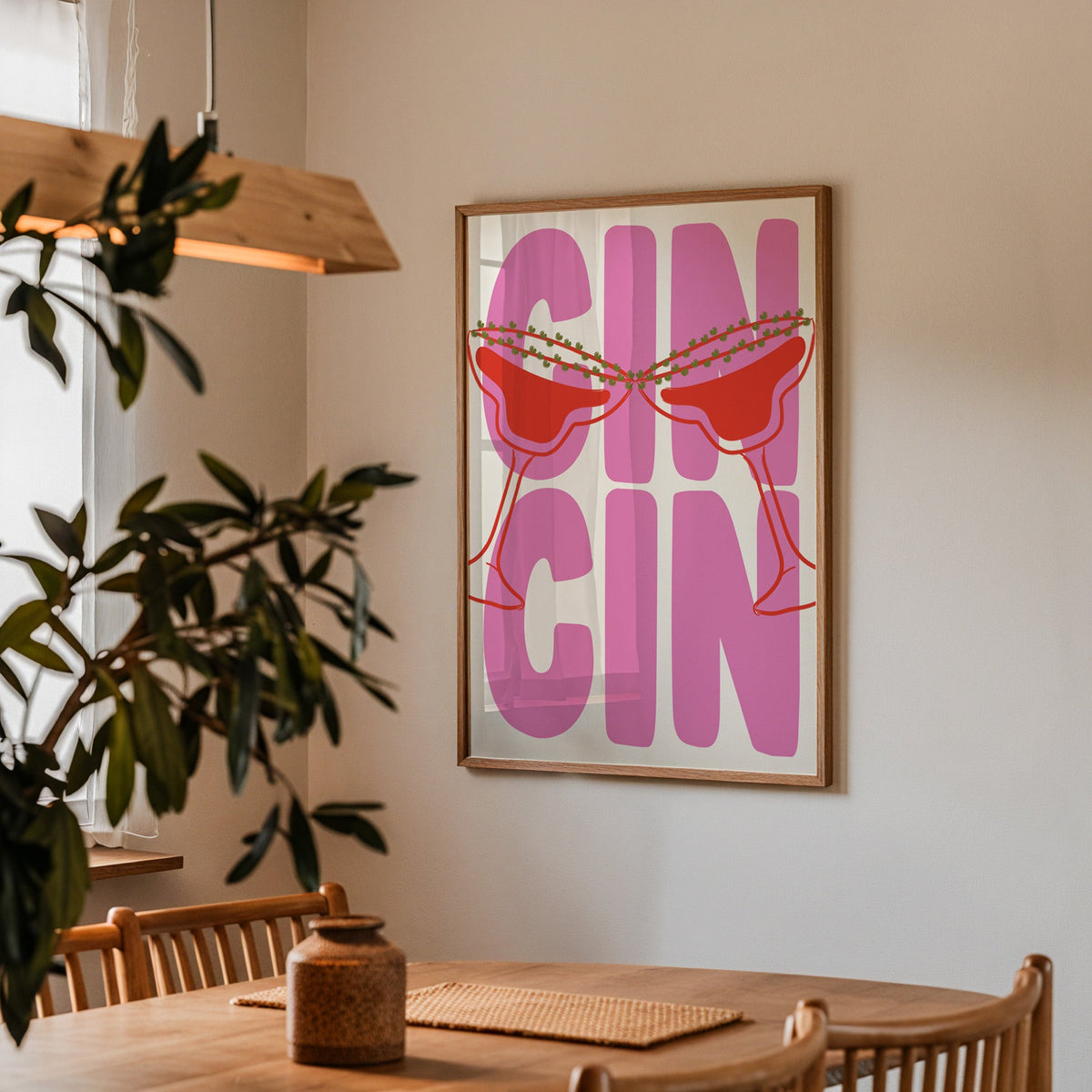 Cin cin pink coupe print in a walnut frame by a dining table and olive tree