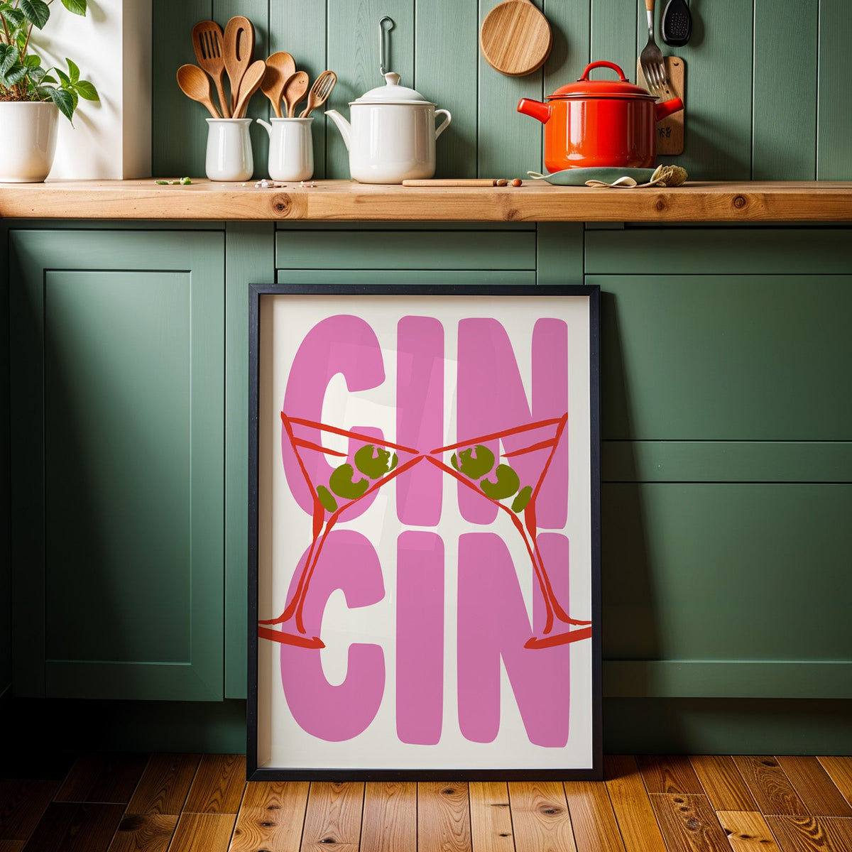 Cin cin red martini print in a black frame against sage green kitchen cabinets