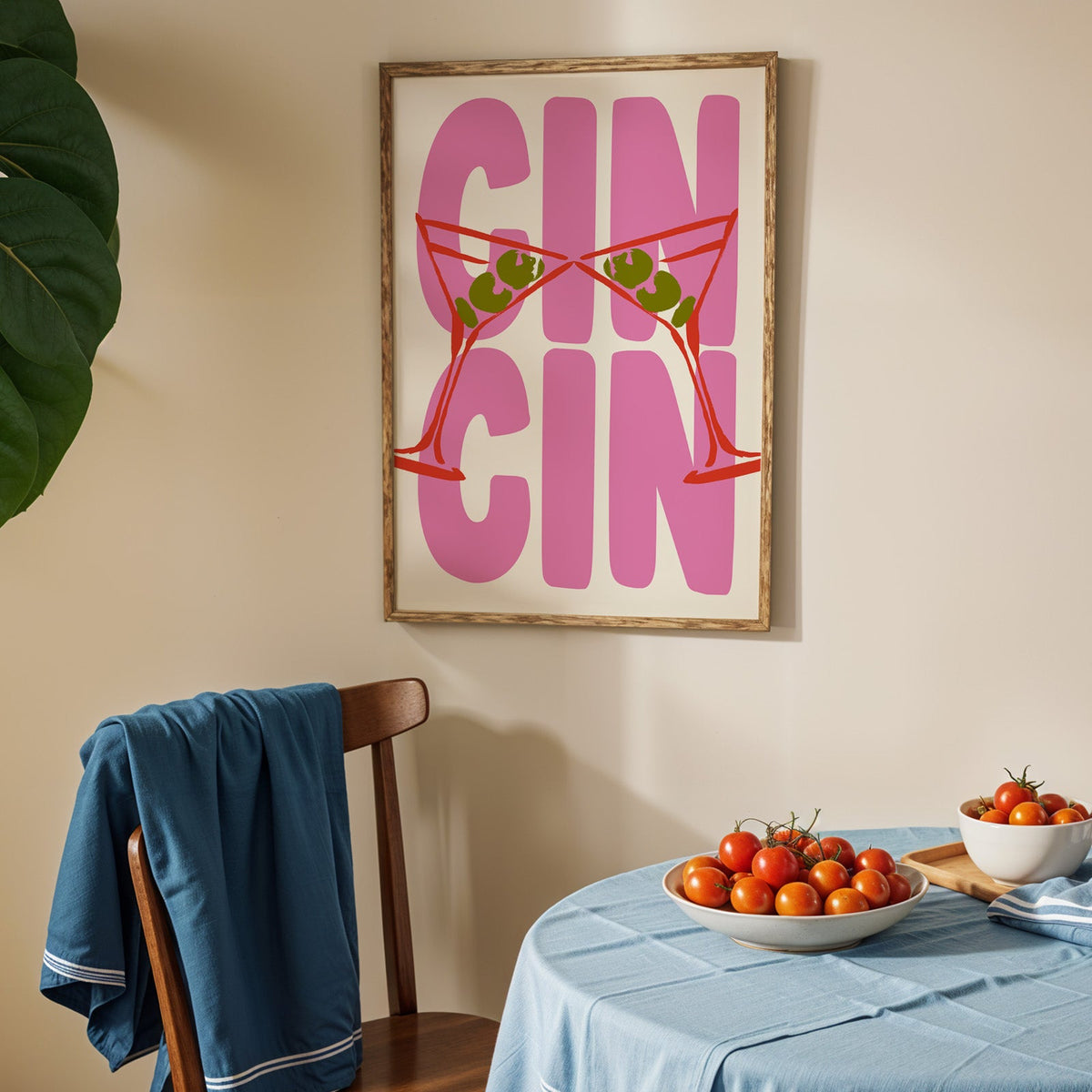 Cin cin red martini print in an oak frame above a blue linen table with ripe tomatoes