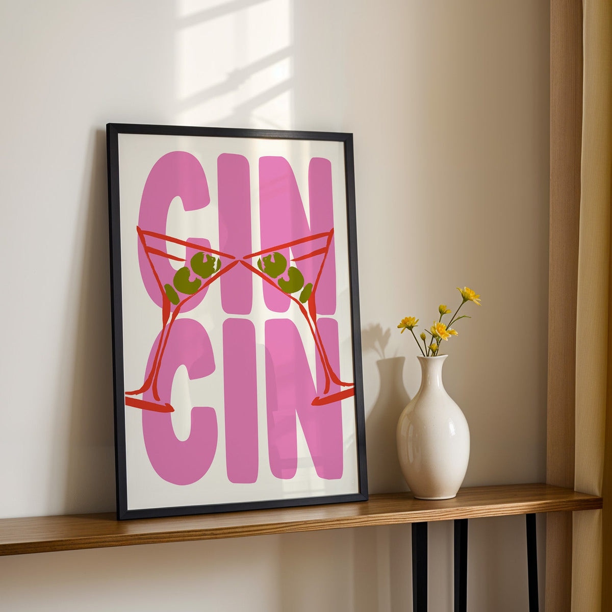 Cin cin red martini print in a black frame on a console table with yellow daisies