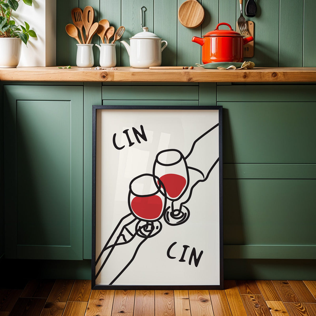 Cin cin red wine line art print in a black frame against sage green kitchen cabinets