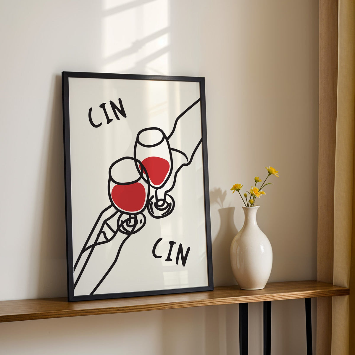 Cin cin red wine line art print in a black frame on a console table with yellow daisies