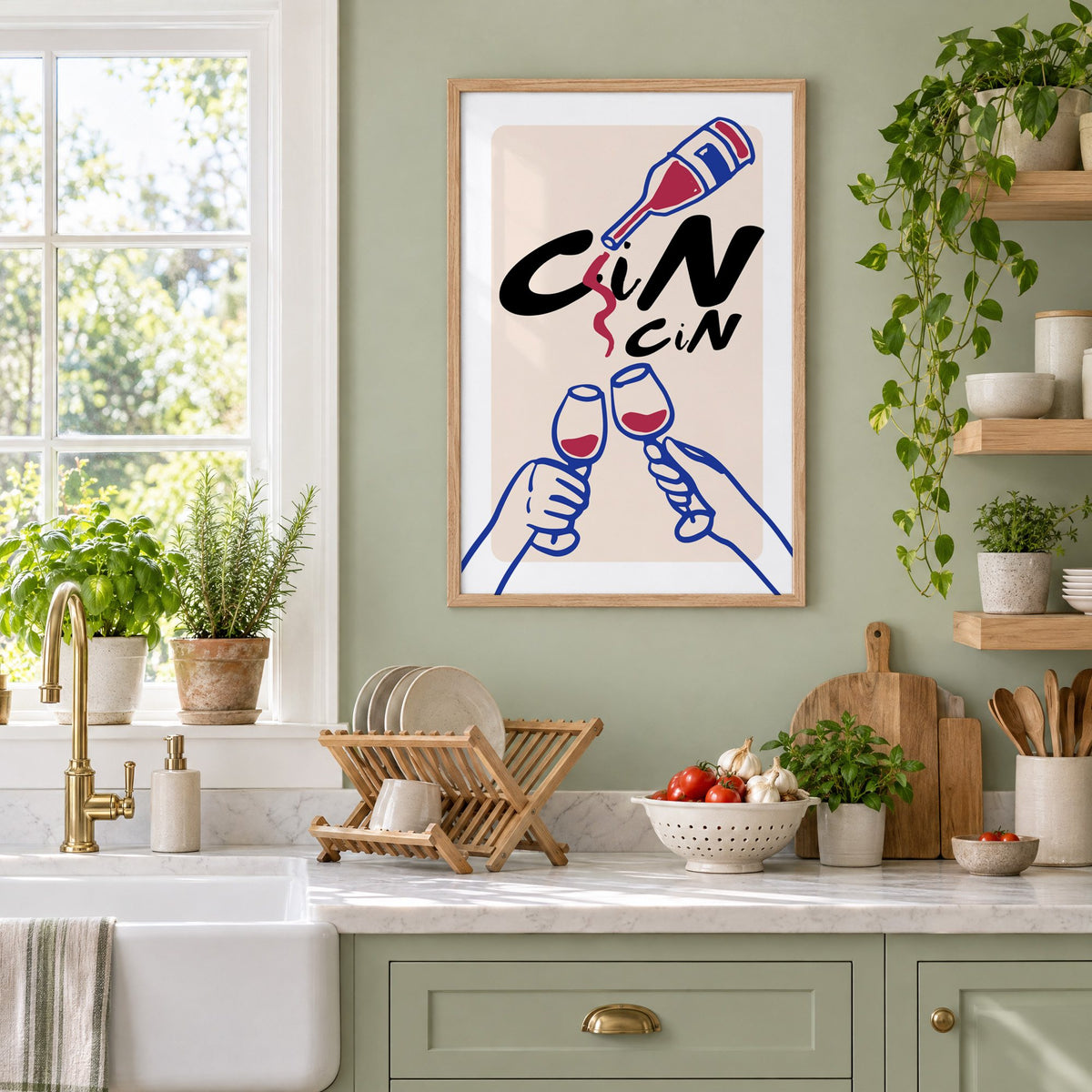 CiN CiN red wine toast print in an oak frame on a sage green kitchen wall beside a farmhouse sink and herbs