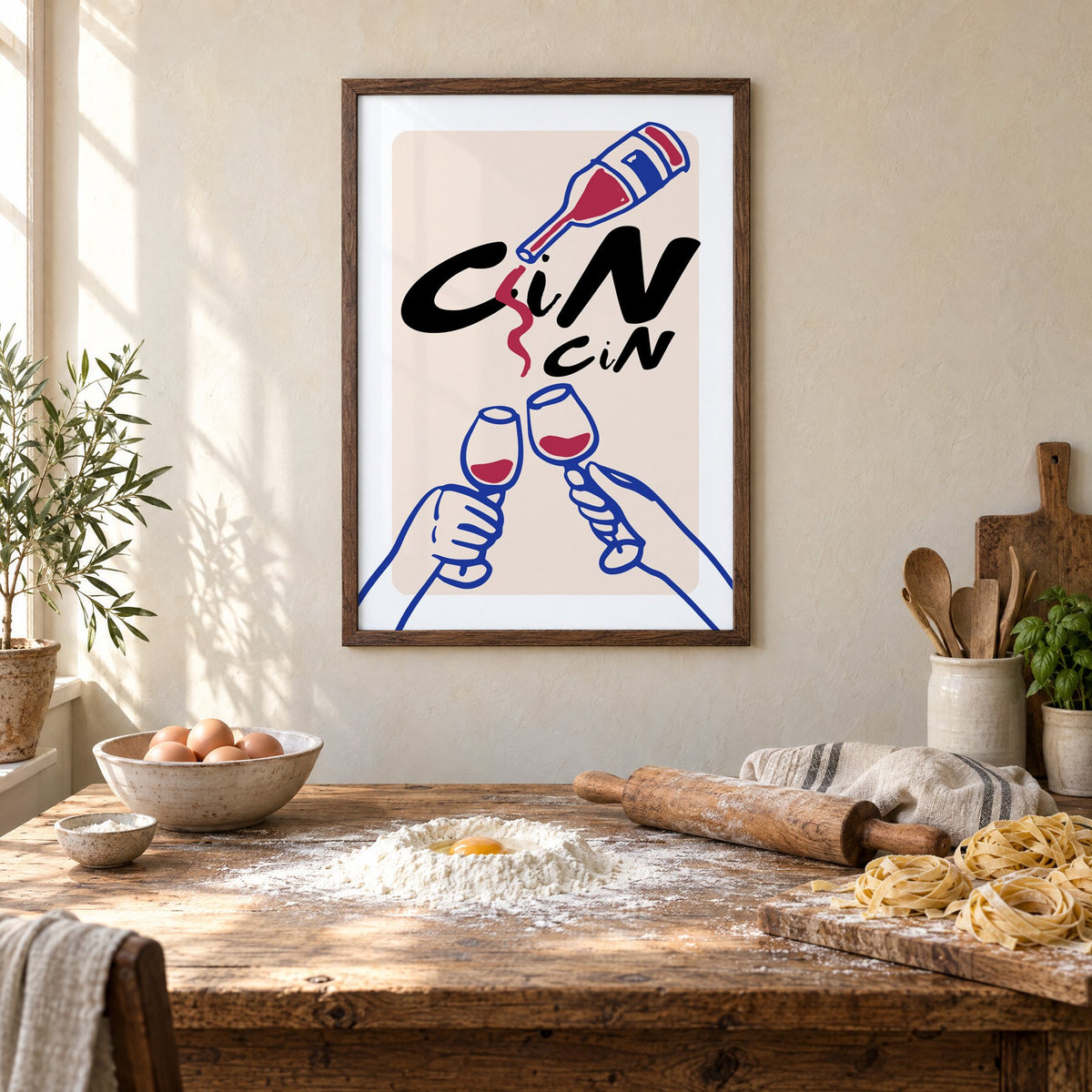 CiN CiN red wine toast print in a walnut frame above a rustic table set for making fresh pasta