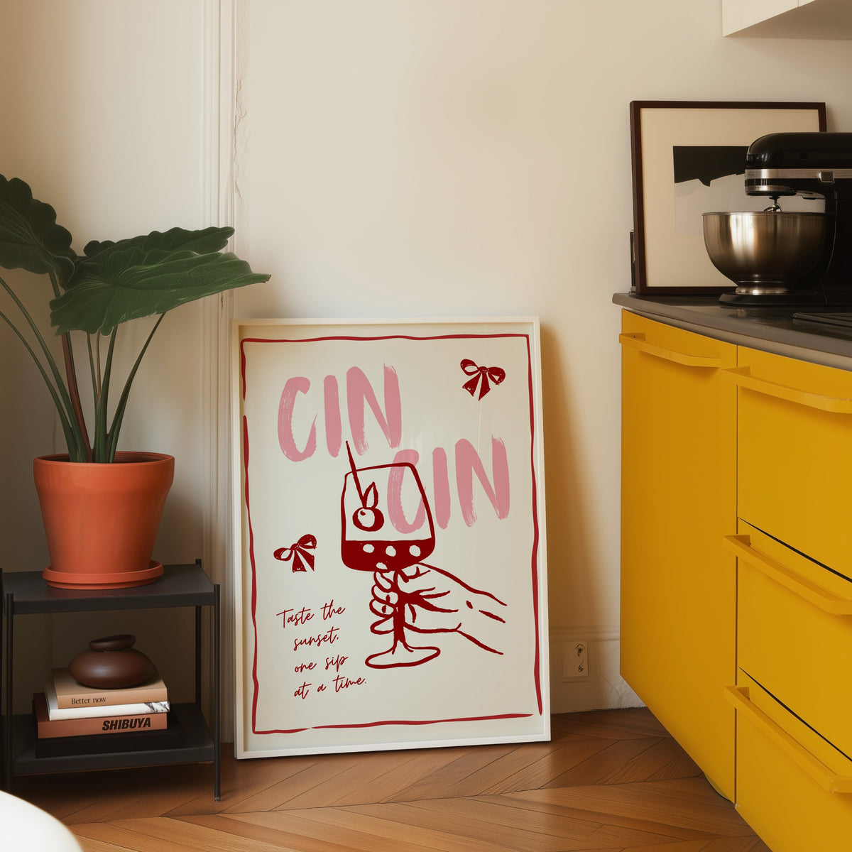 Cin Cin wine print in a white frame leaning on parquet beside a bright yellow kitchen