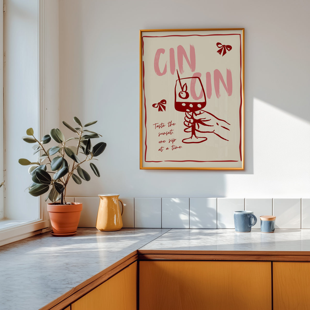 Cin Cin wine print in a gold frame above a marble counter with a yellow ceramic jug