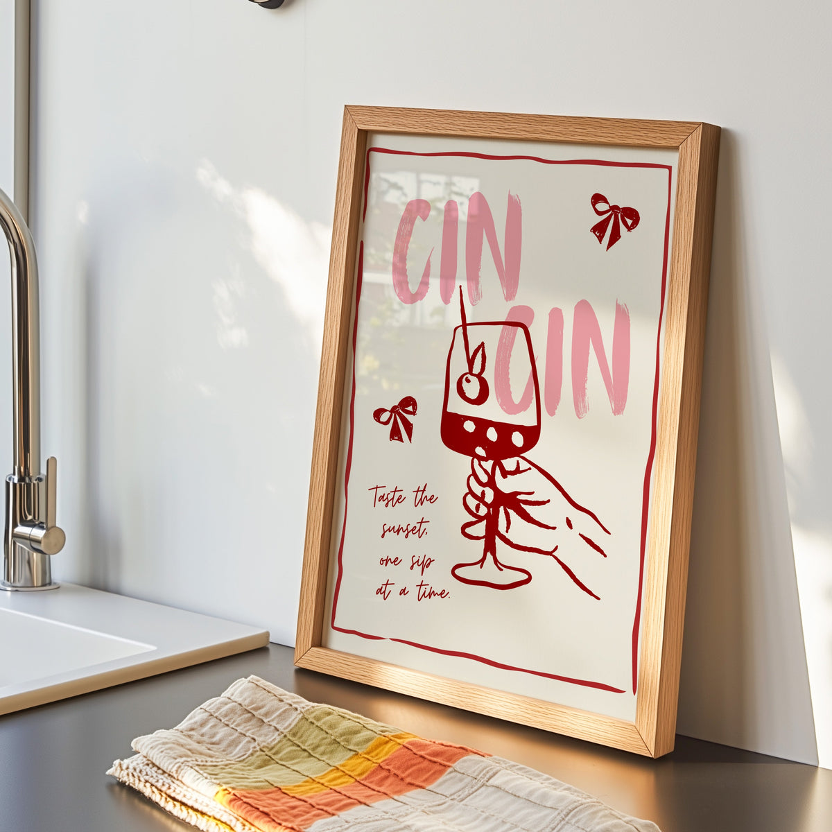 Cin Cin wine print in an oak frame by the kitchen sink beside a striped tea towel