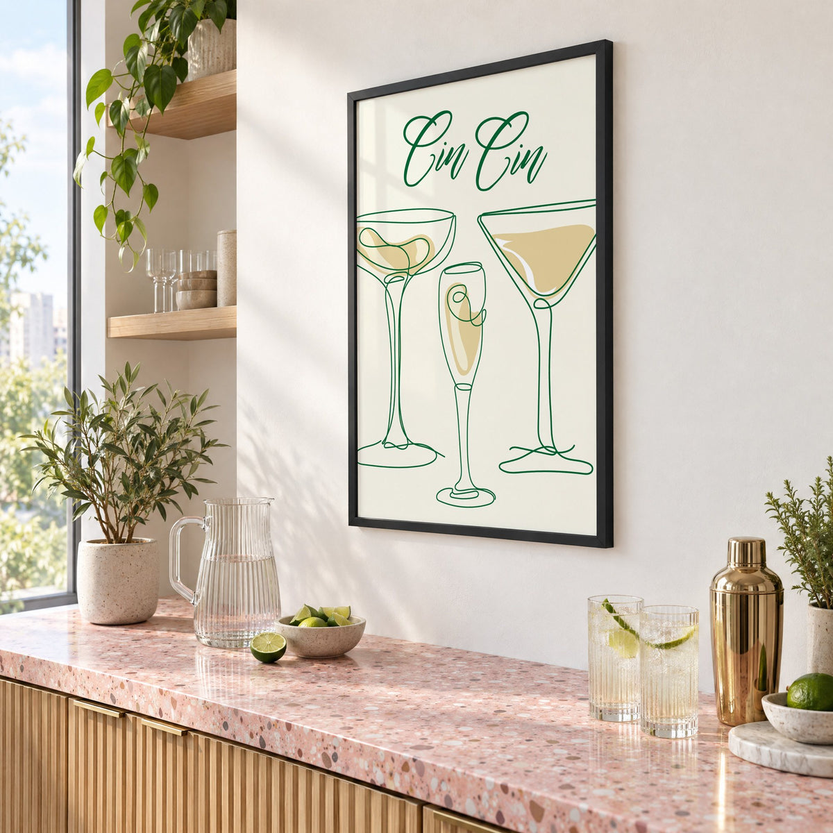 Cin Cin one-line coupe, flute and martini print in a black frame above a pink terrazzo cocktail counter with limes, seen at an angle