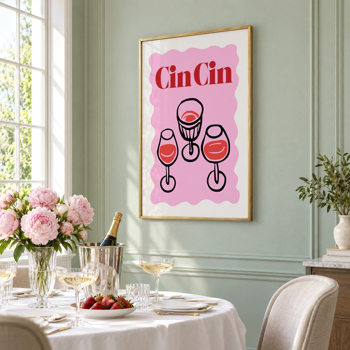 Cin Cin three glasses top view print in a brass frame on a sage wall above a brunch table with champagne and peonies, seen at an angle