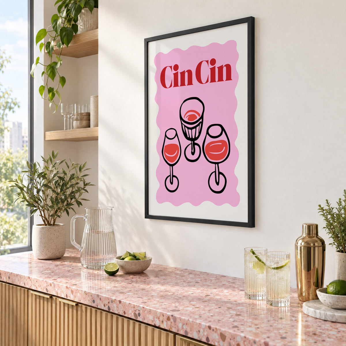Cin Cin three glasses top view print in a black frame above a pink terrazzo cocktail counter with limes, seen at an angle