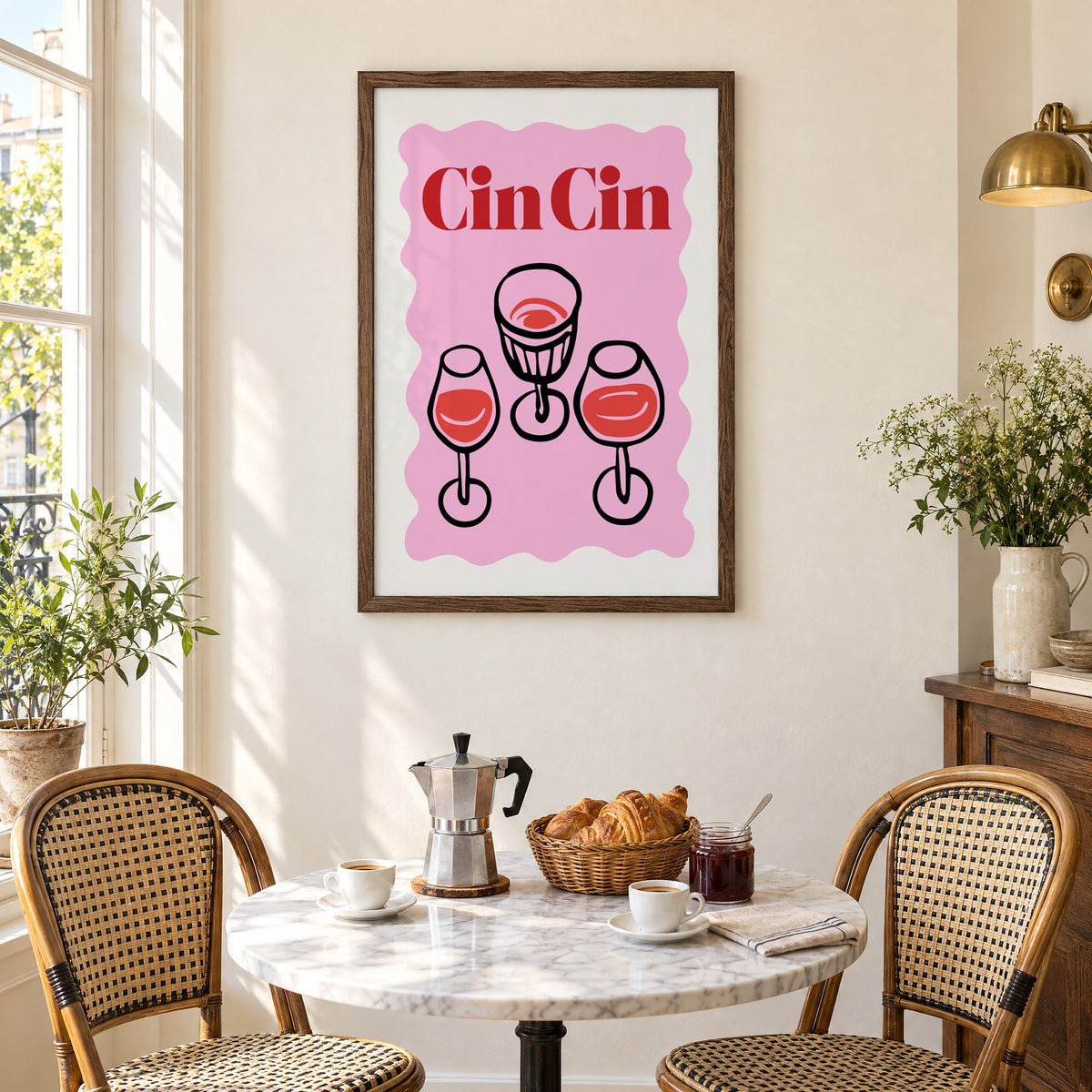 Cin Cin three glasses top view print in a walnut frame above a marble bistro table with croissants and rattan chairs