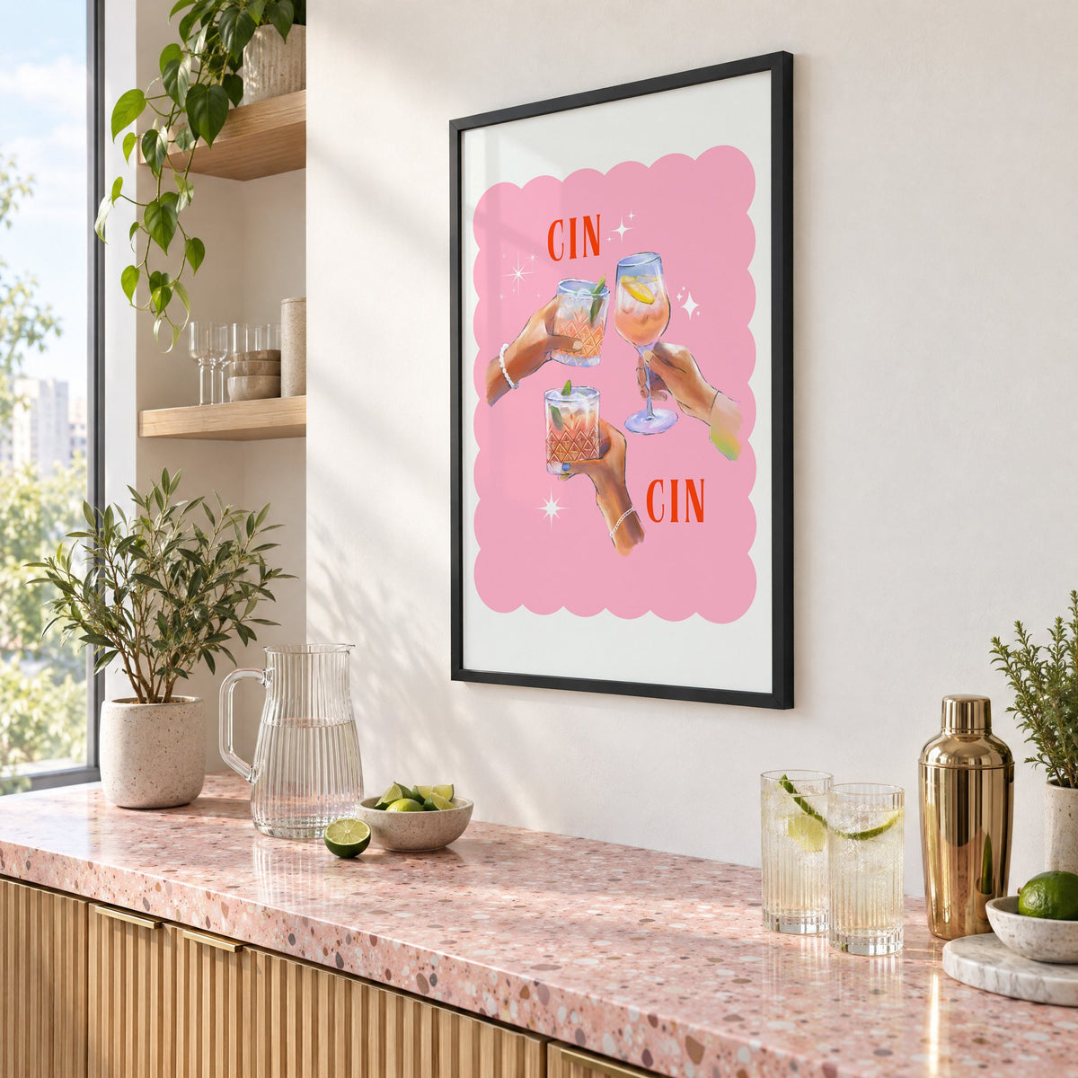 Cin Cin three hands toasting print in a black frame above a pink terrazzo cocktail counter with limes, seen at an angle