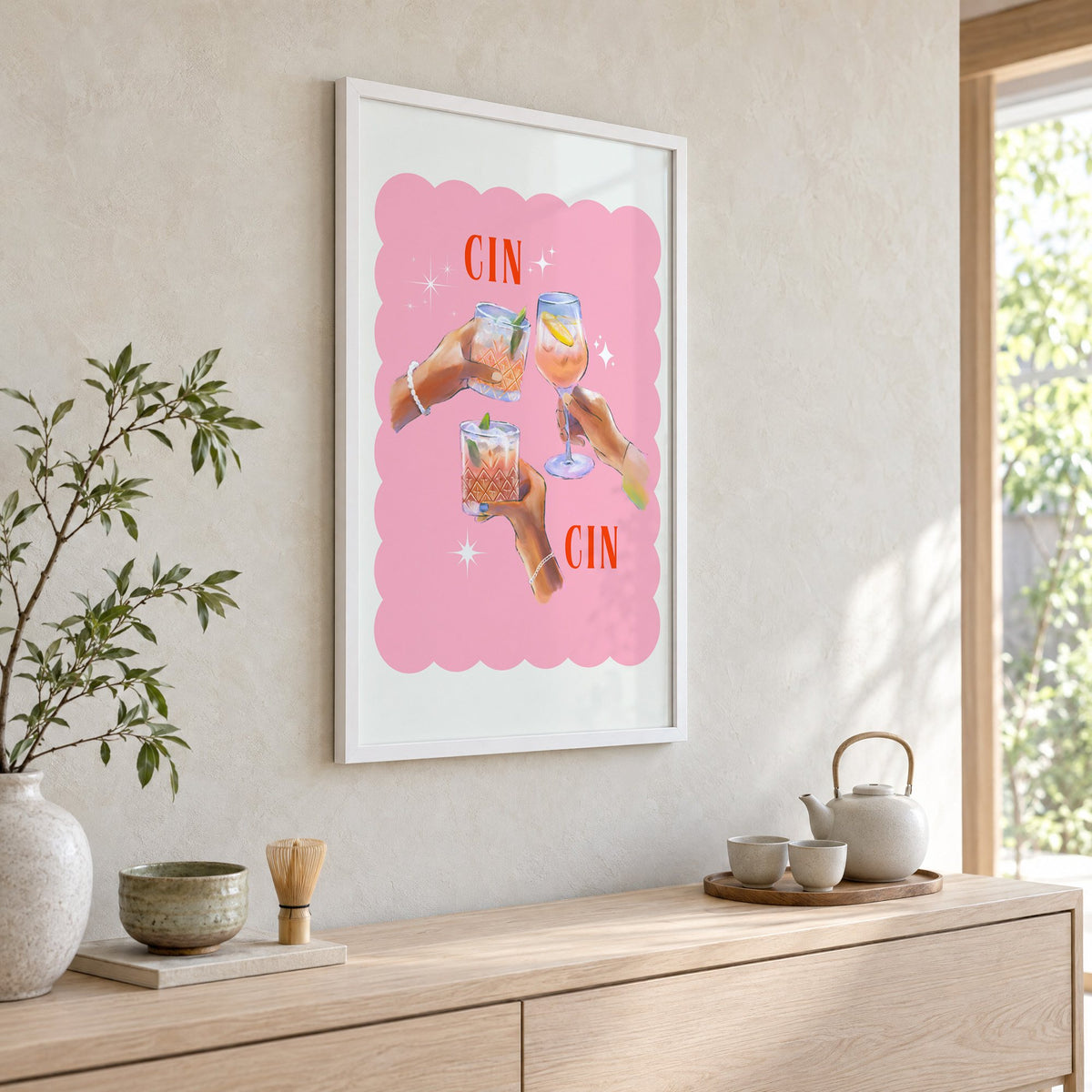 Cin Cin three hands toasting print in a white frame above a pale wood console with a matcha tea set