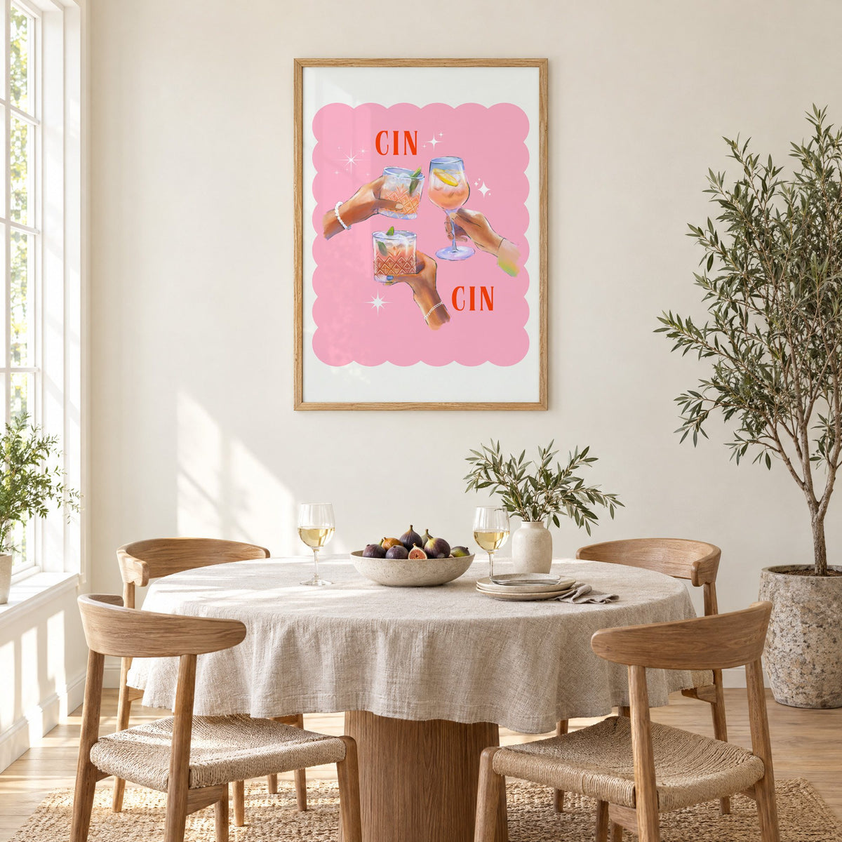 Cin Cin three hands toasting print in an oak frame above a round linen-covered dining table with figs and wine
