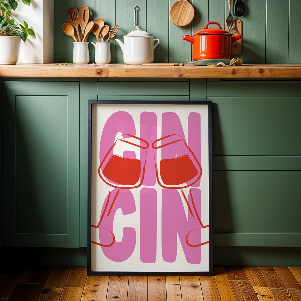 Cin cin wine glasses print in a black frame against sage green kitchen cabinets