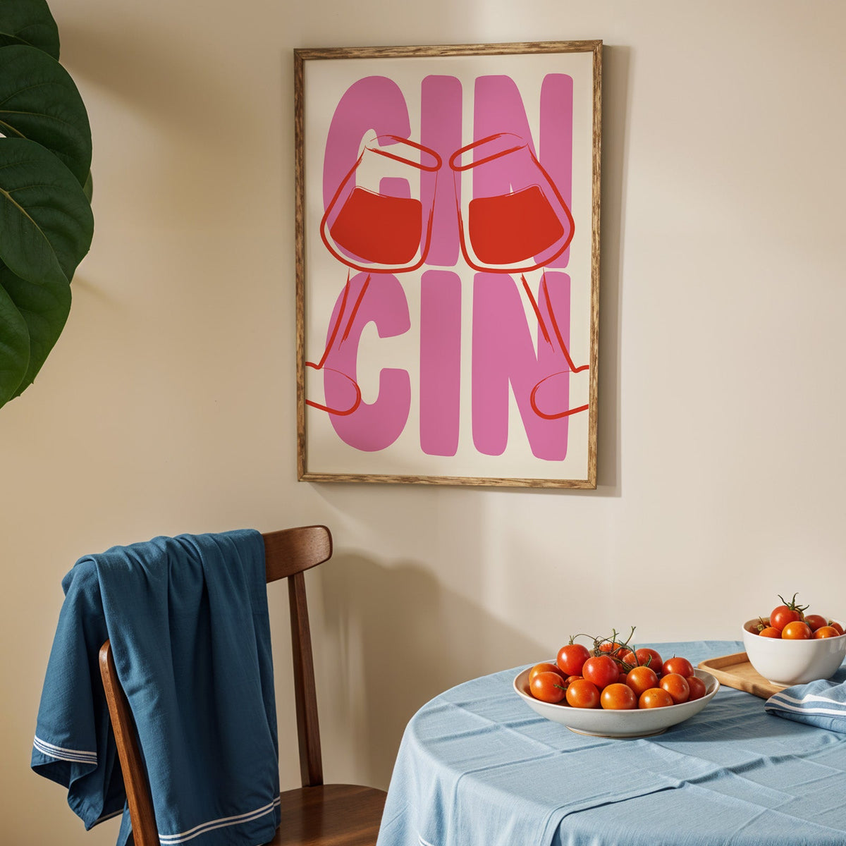 Cin cin wine glasses print in an oak frame above a blue linen table with ripe tomatoes