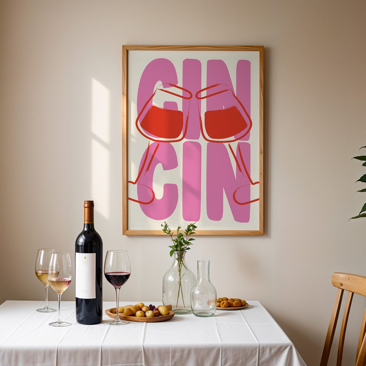 Cin cin wine glasses print in an oak frame above a table laid with red wine and glasses