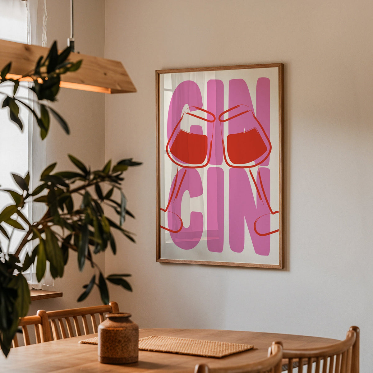Cin cin wine glasses print in a walnut frame above a dining table beside an olive tree