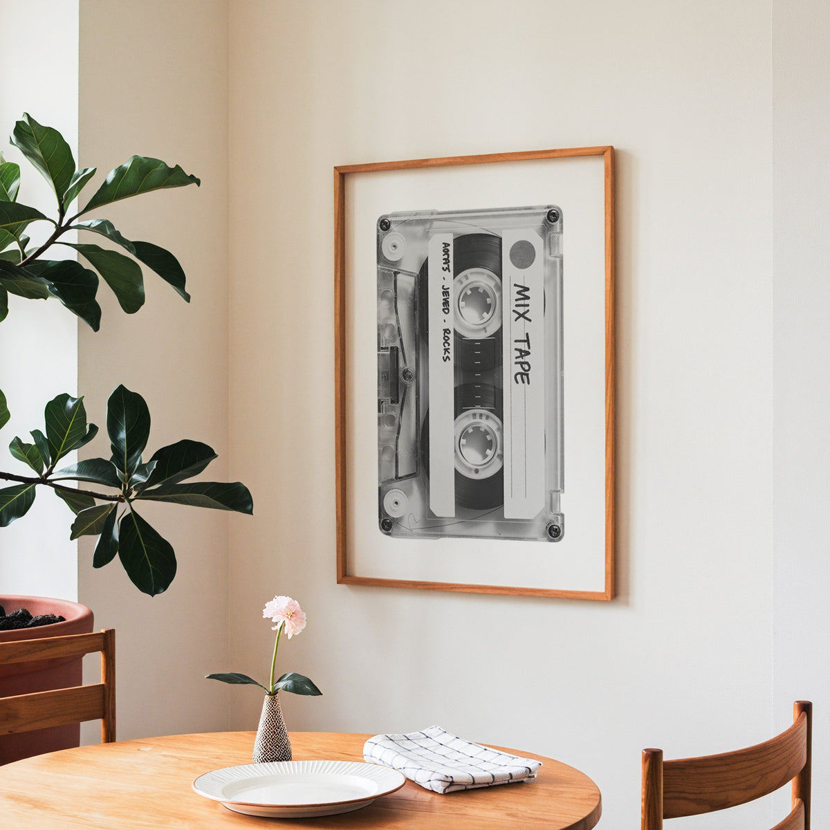 Clear mix tape cassette with handwritten label print in a teak frame above a round wooden dining table