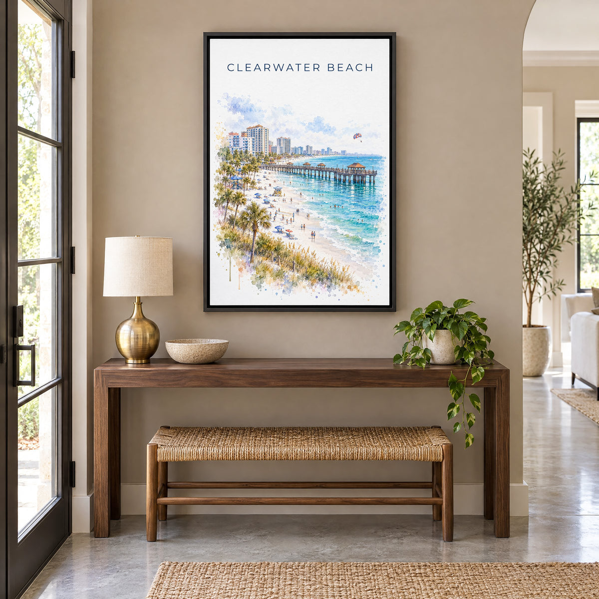 Clearwater Beach watercolor print as a black floater canvas above a walnut console and woven bench in an entryway