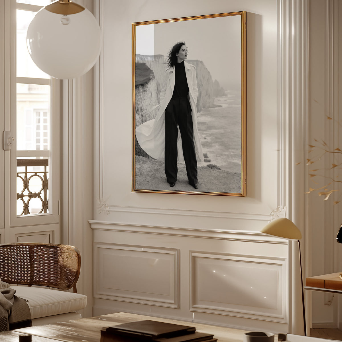 Black and white model in white trench on cliffs print shown in a gold frame in a Parisian paneled living room