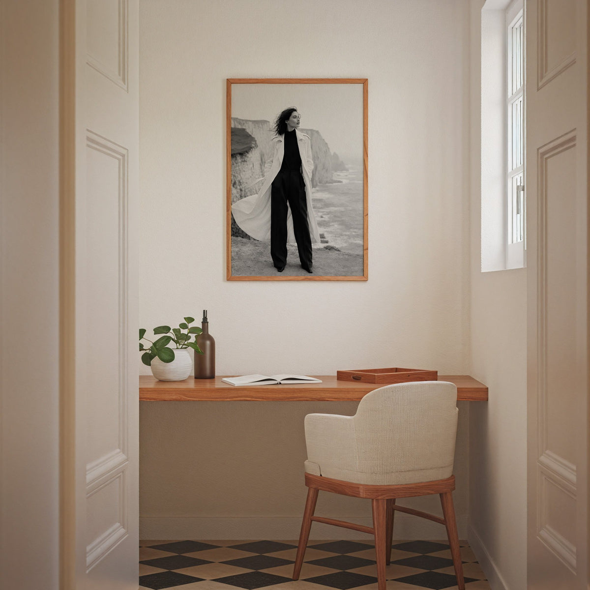 Black and white model in white trench on cliffs print in an oak frame above a home office desk nook