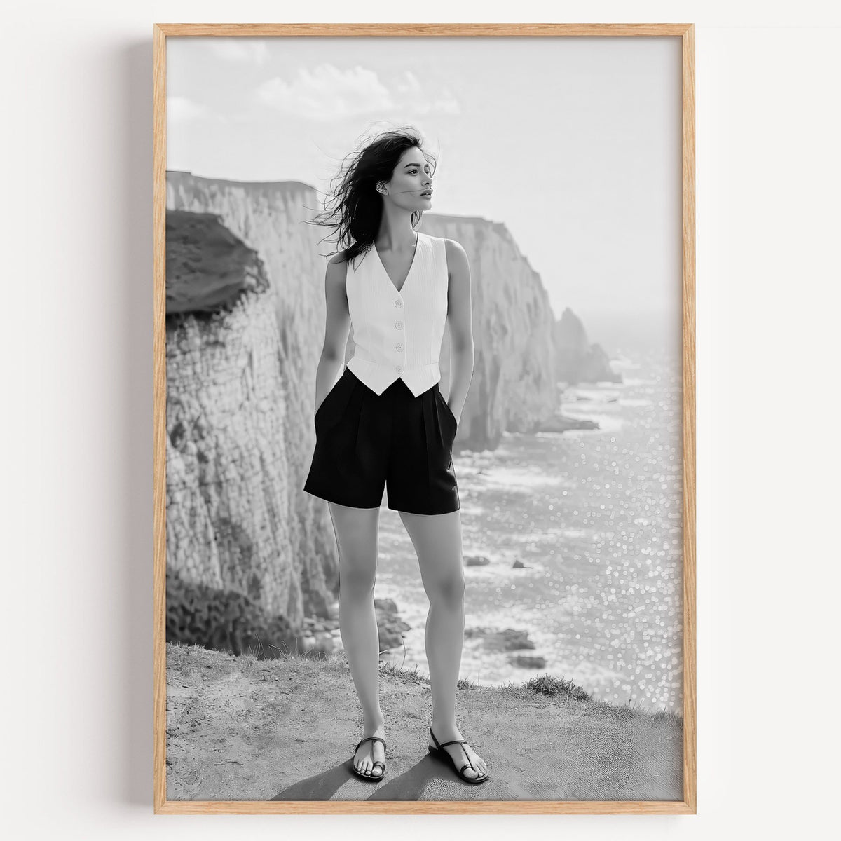 Black and white model in white vest on cliffs print in a light oak frame on a plain white wall