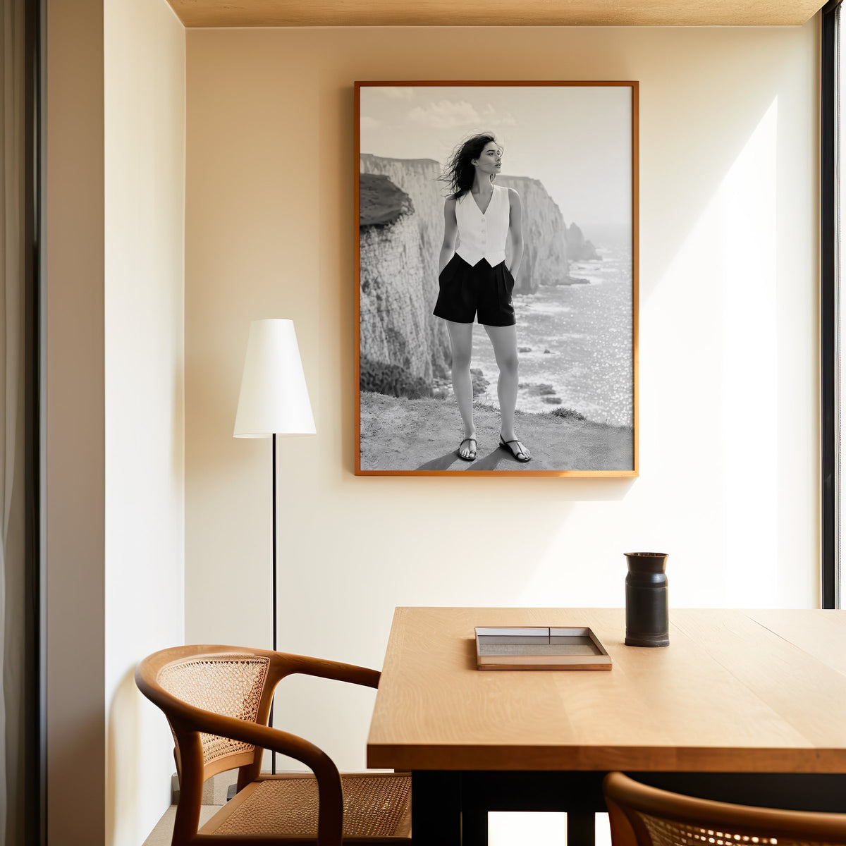 Black and white model in white vest on cliffs print in an oak frame above a dining table and cane chair