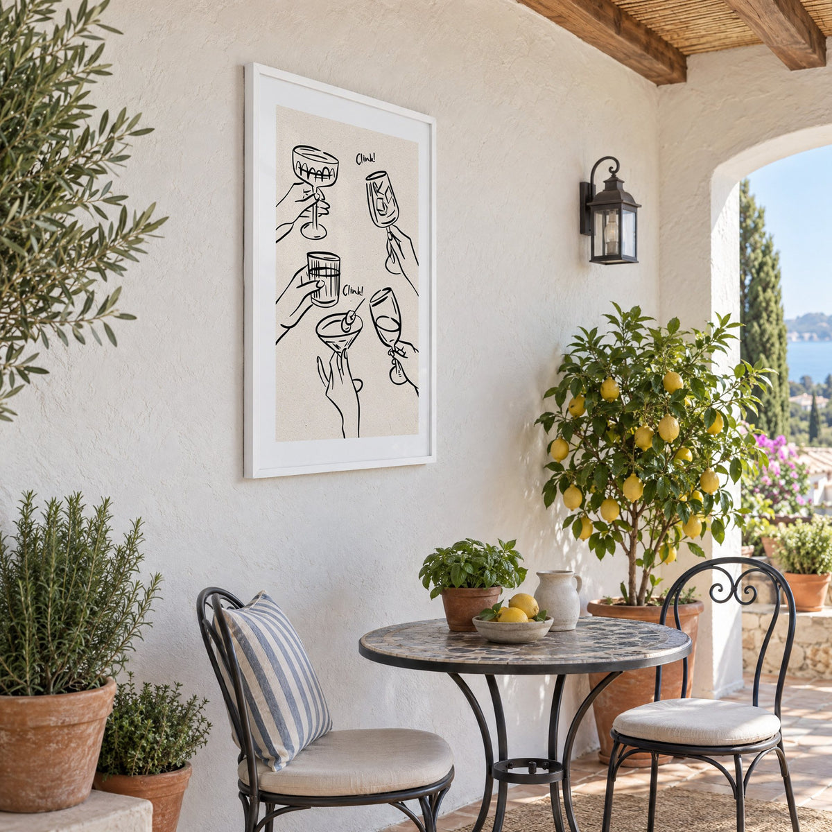 Clink! black line-art cocktail toast print in a white frame on a sunny patio wall beside a potted lemon tree