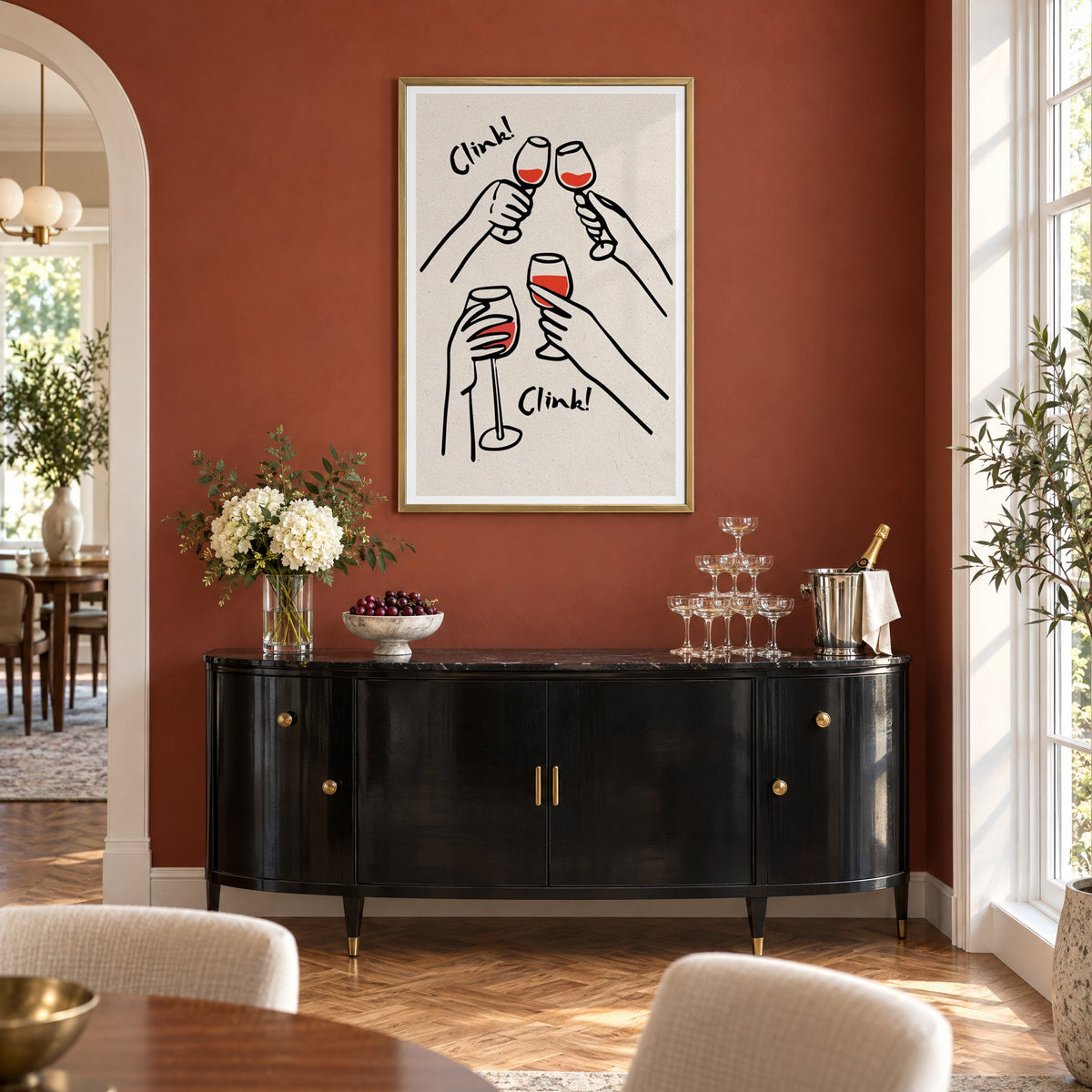 Clink! red wine toast kraft print in a brass frame on a terracotta wall above a black buffet with a champagne tower