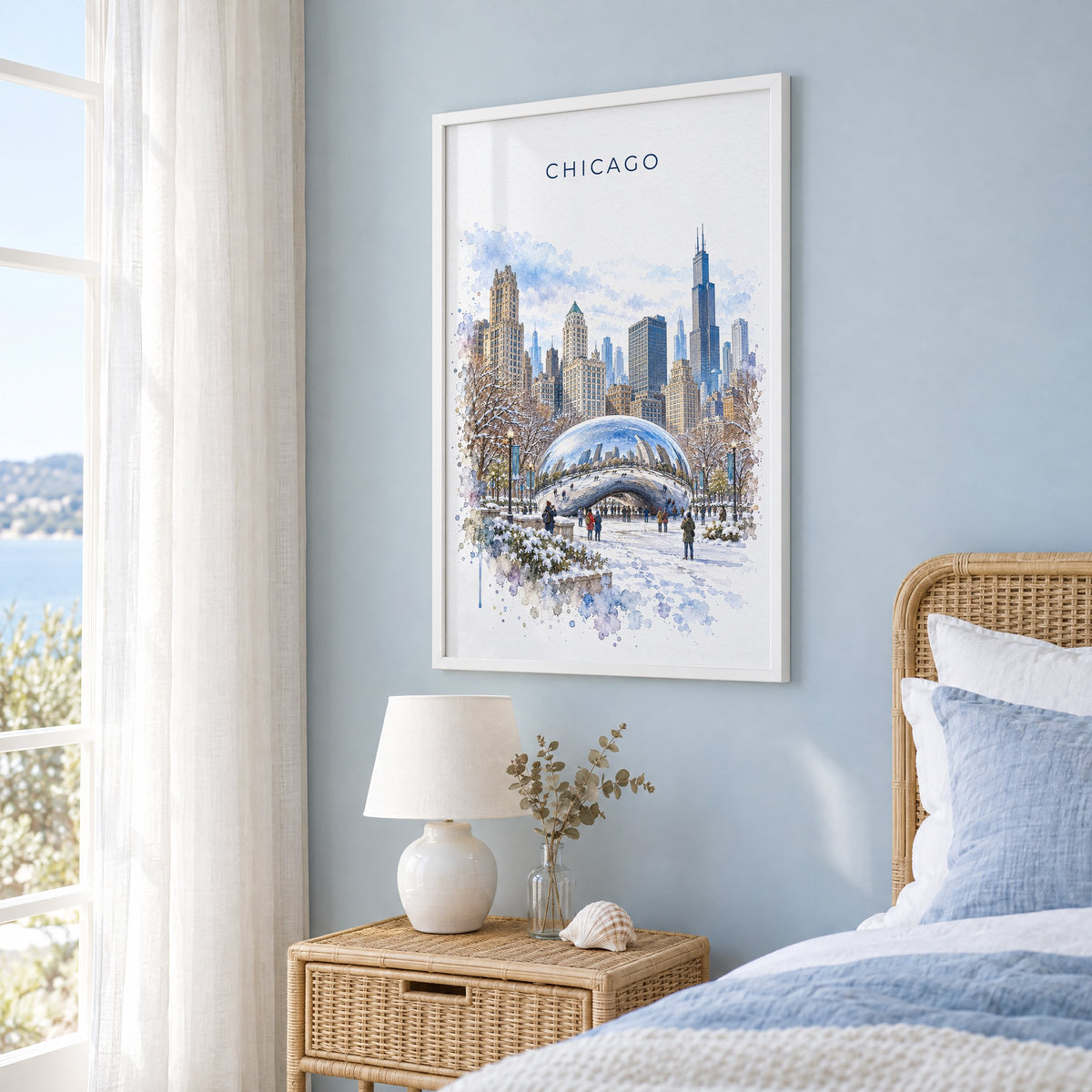 Cloud Gate watercolor print in a white frame on a pale blue wall beside a rattan bed in a coastal bedroom