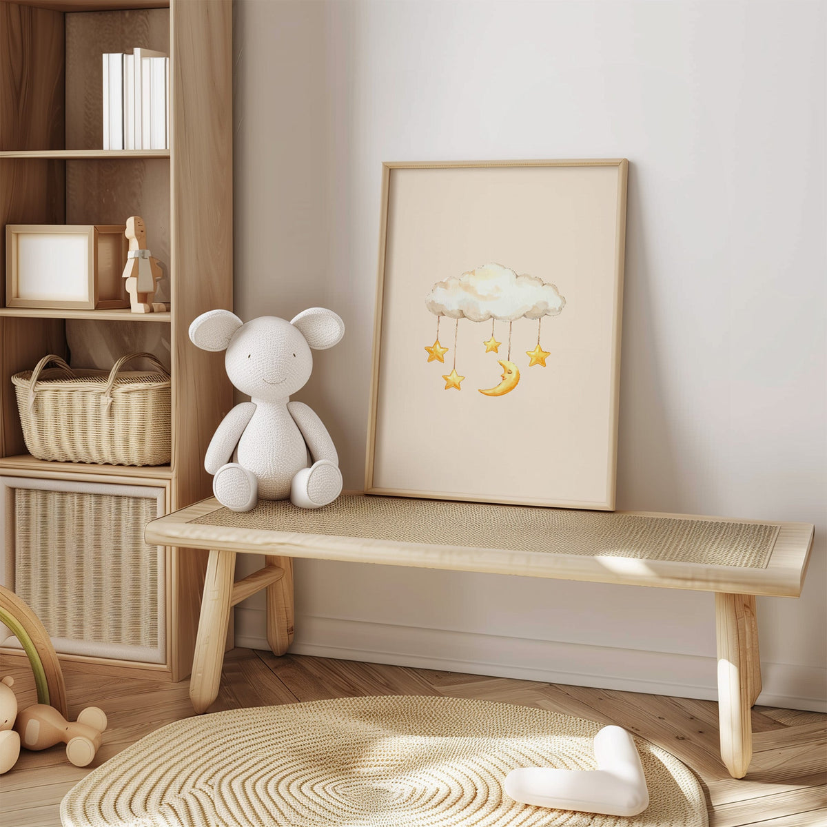 Cloud mobile with moon and stars nursery print in an oak frame on a cane bench beside a white knit plush