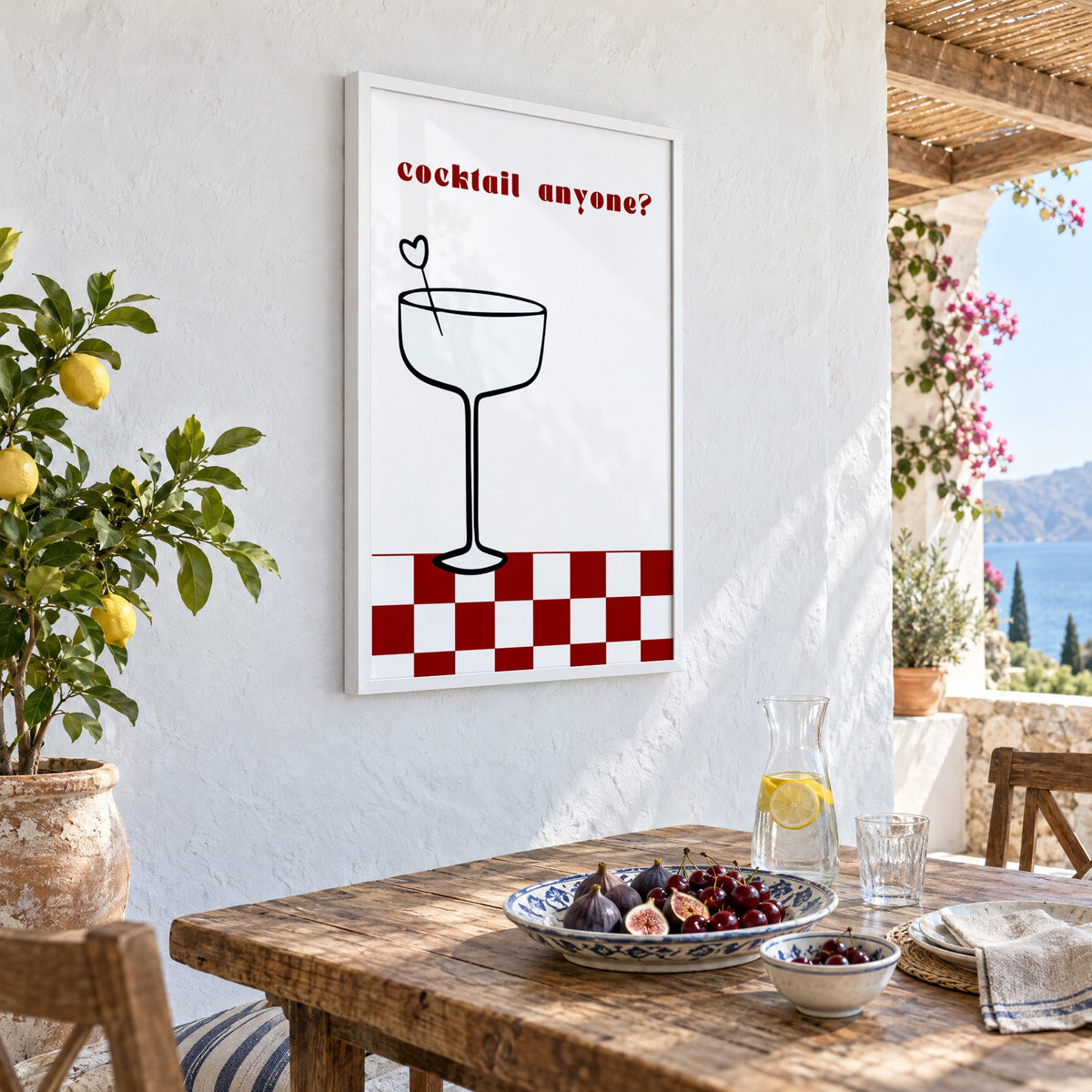 cocktail anyone? coupe check floor print in a white frame on a whitewashed terrace wall above a lunch table with figs and cherries, seen at an angle