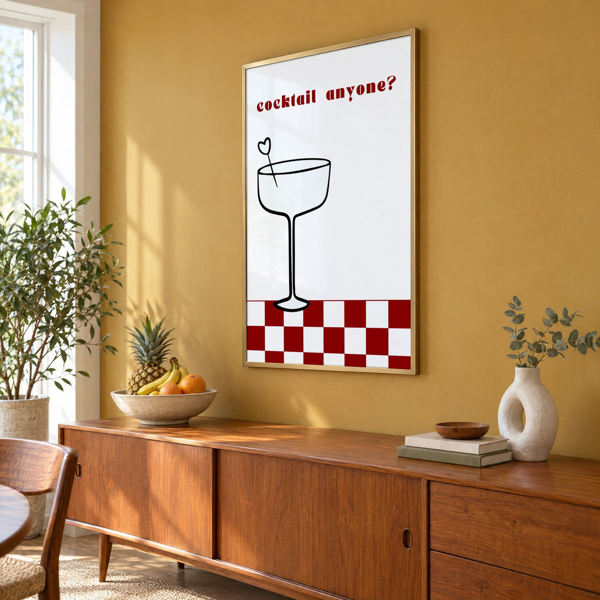 cocktail anyone? coupe check floor print in a brass frame on a mustard wall above a teak sideboard with a fruit bowl, seen at an angle