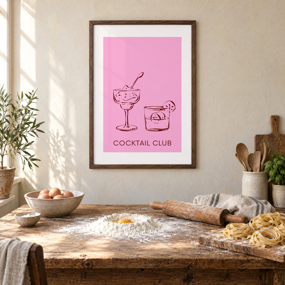 Cocktail Club sketched glasses pink print in a walnut frame above a rustic table set for making fresh pasta