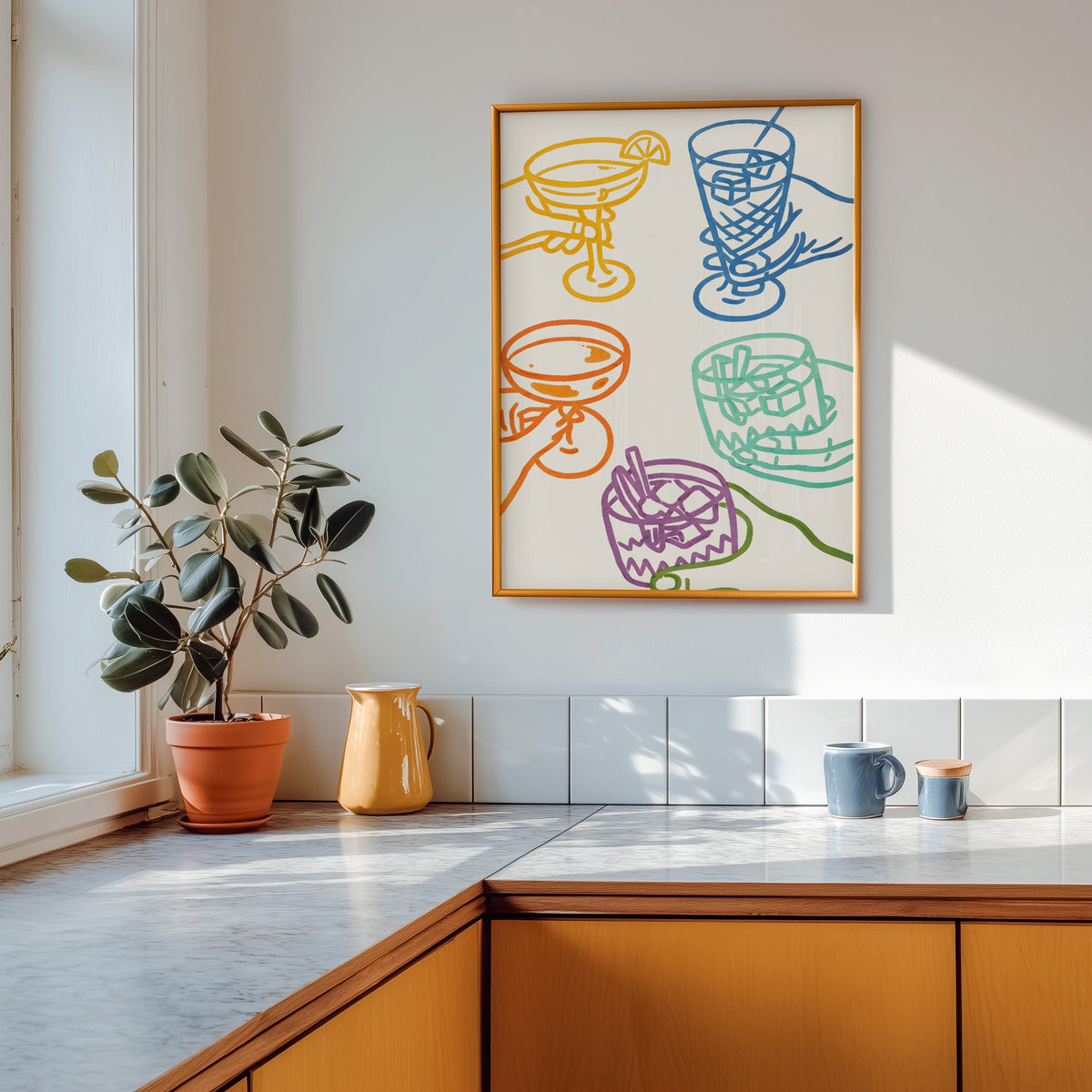 Cocktail glasses print in a gold frame above a marble counter with a yellow ceramic jug