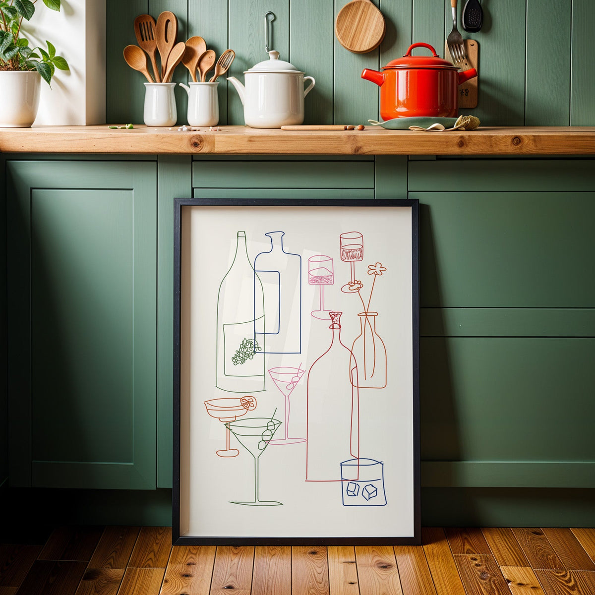 Cocktail glassware line art print in a black frame against sage green kitchen cabinets