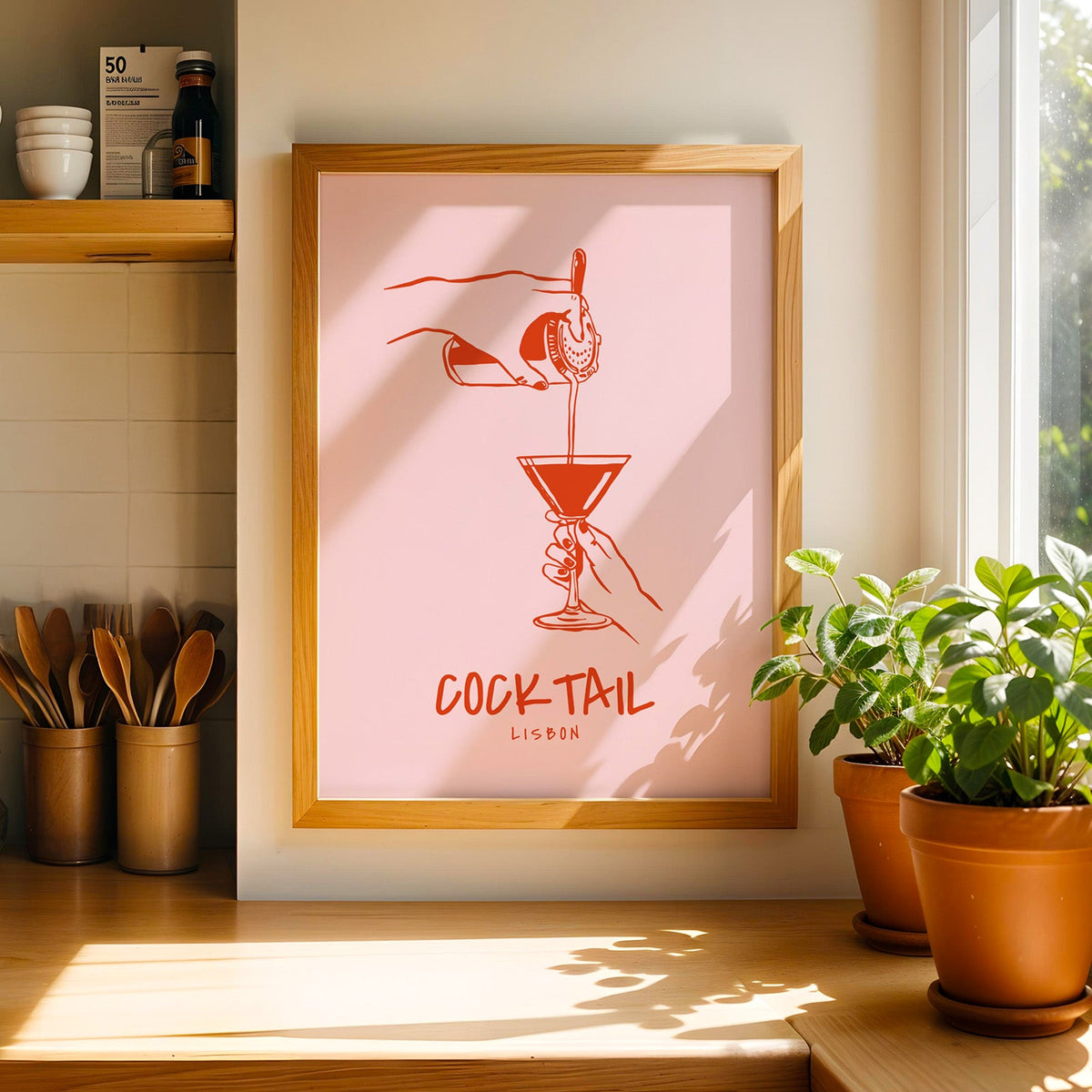 Cocktail Lisbon print in a light pine frame beside a ceramic jar of wooden spoons