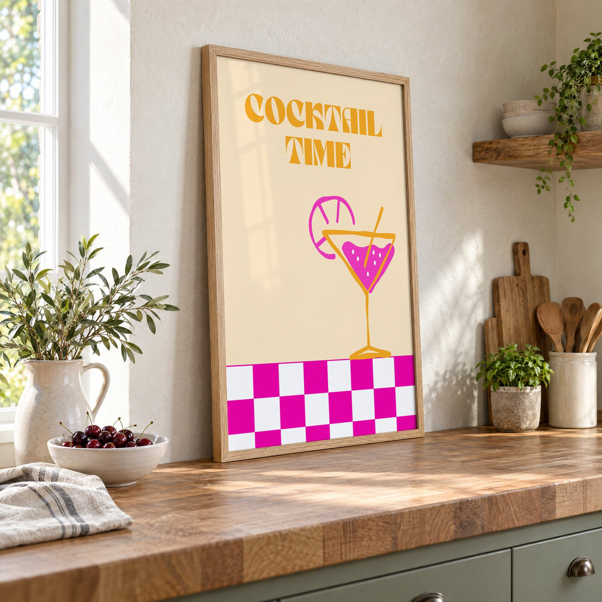 Cocktail Time martini checkerboard print in an oak frame leaning on a butcher block island beside a bowl of cherries
