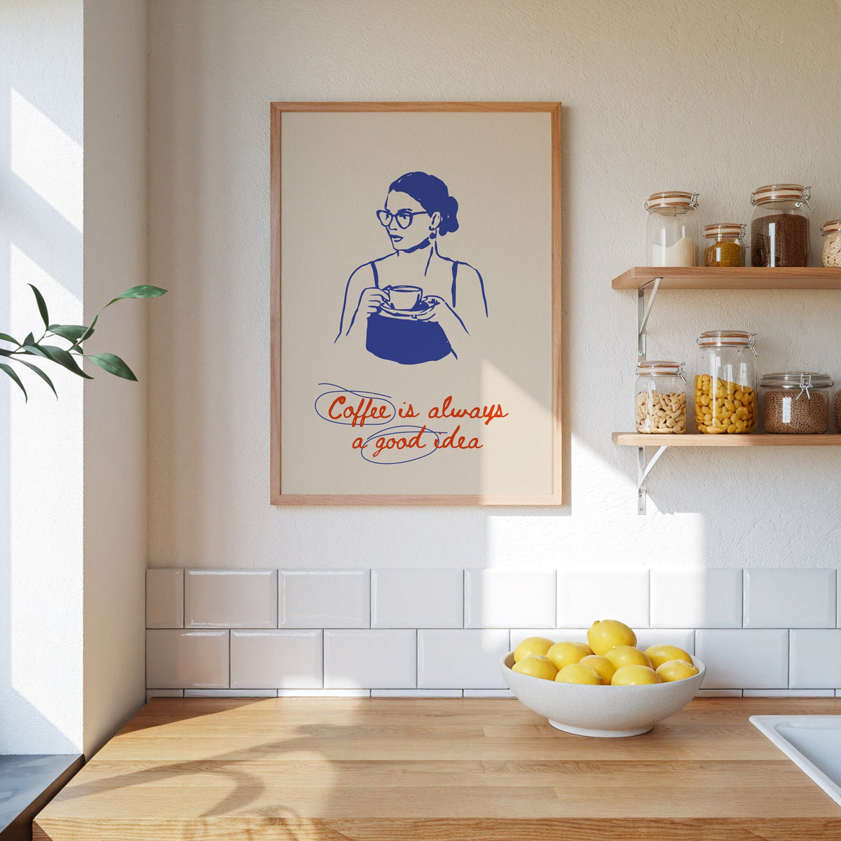 Coffee Is Always a Good Idea print in an oak frame beside open kitchen shelves