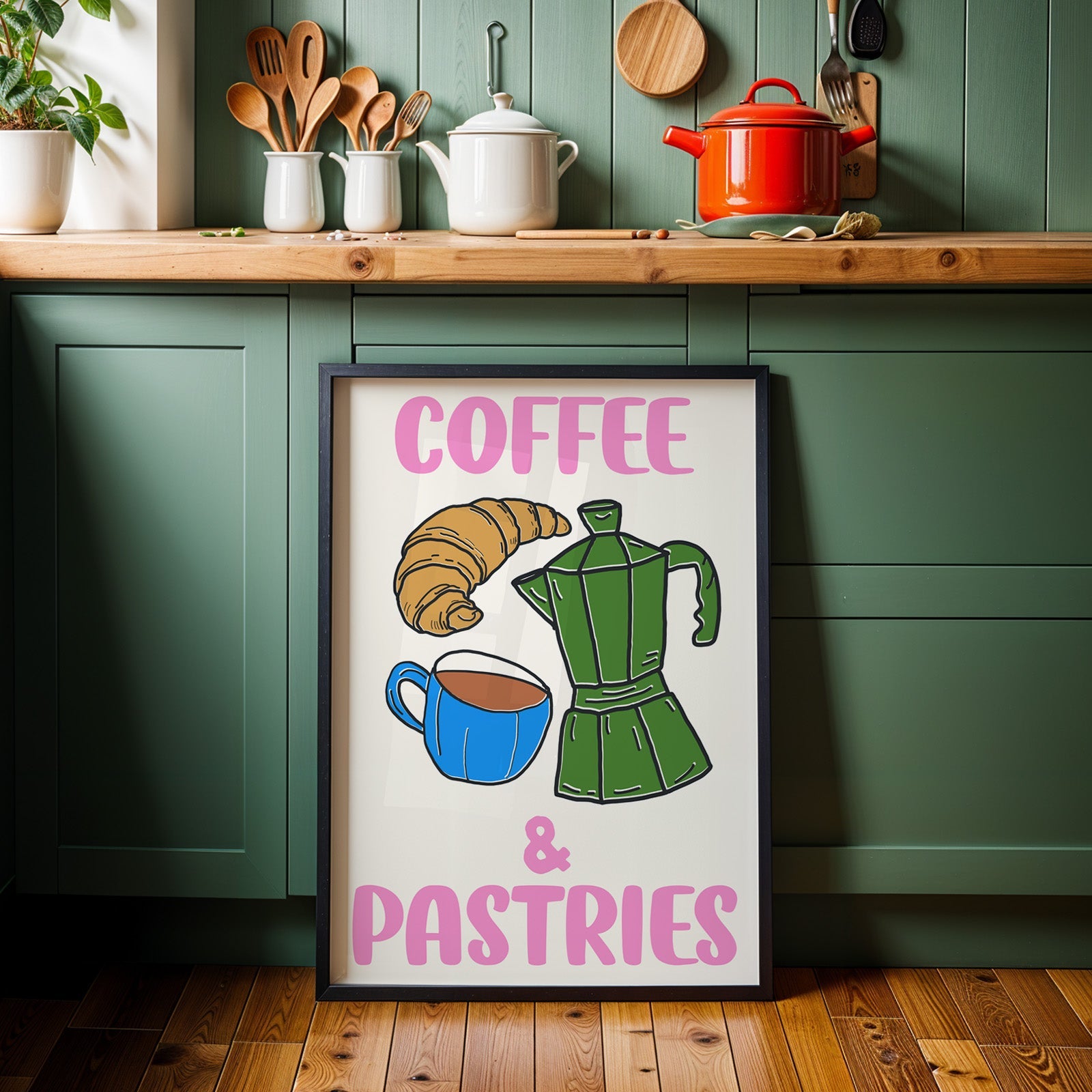 Coffee and pastries print in a black frame against sage green kitchen cabinets