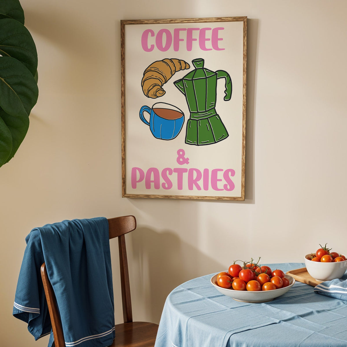 Coffee and pastries print in an oak frame above a blue linen table with ripe tomatoes