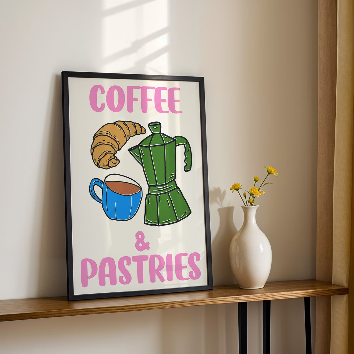 Coffee and pastries print in a black frame on a console table with yellow daisies