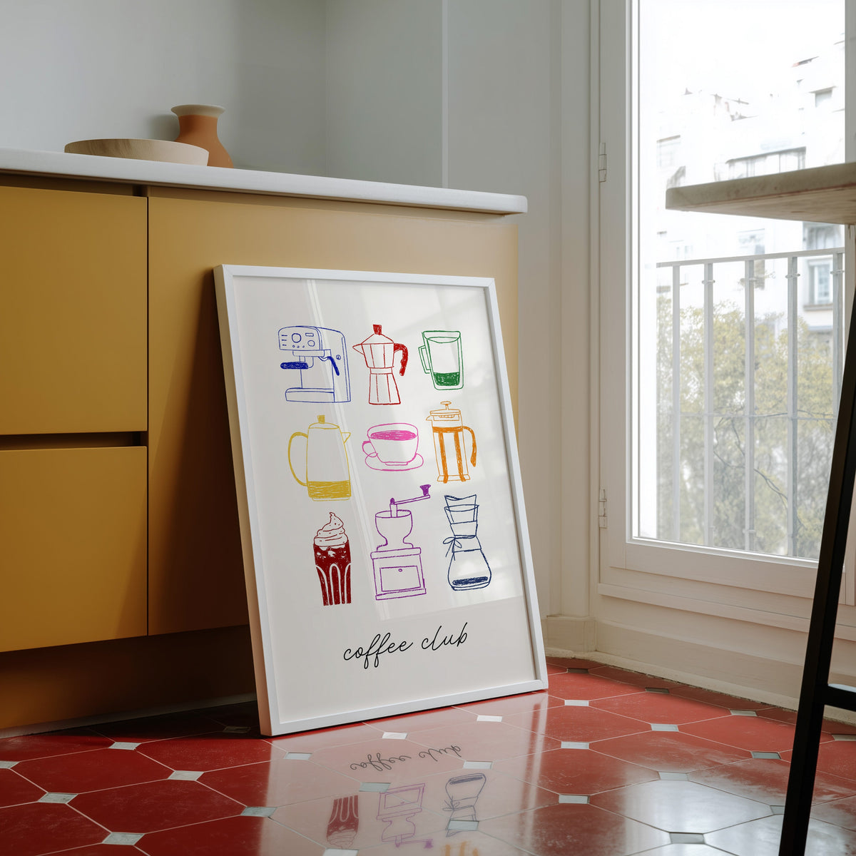 Coffee club print in a white frame against yellow cabinets on a red tiled floor