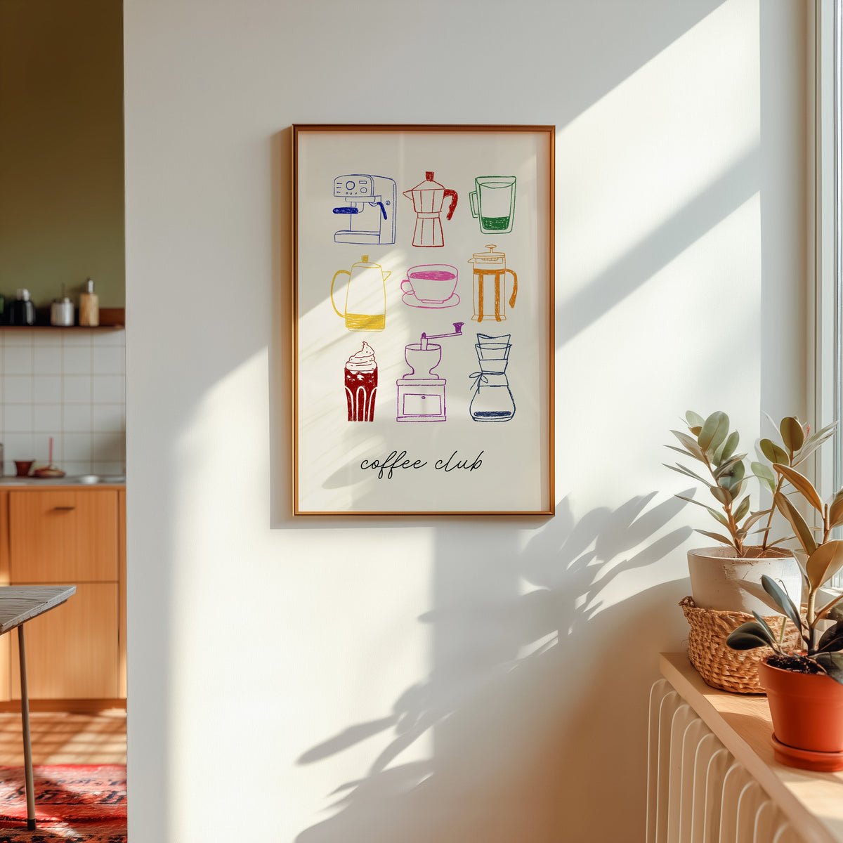 Coffee club print in a gold frame in sunlight with plants on the ledge and a kitchen beyond