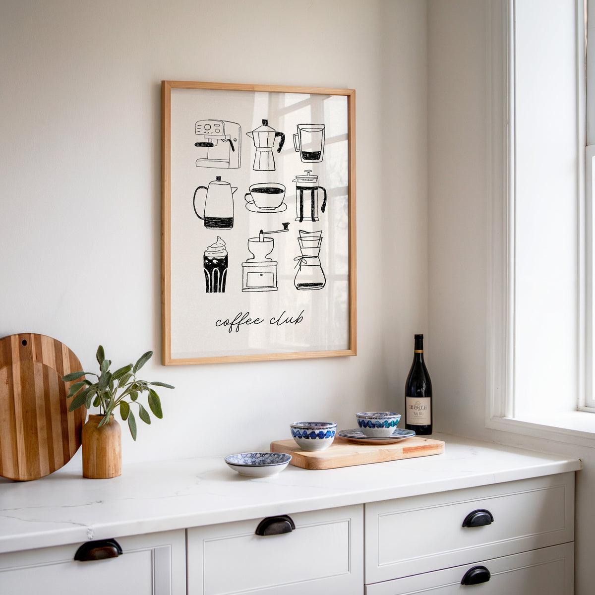 Coffee Club brewer grid print in an oak frame above a white sideboard with a bottle of wine