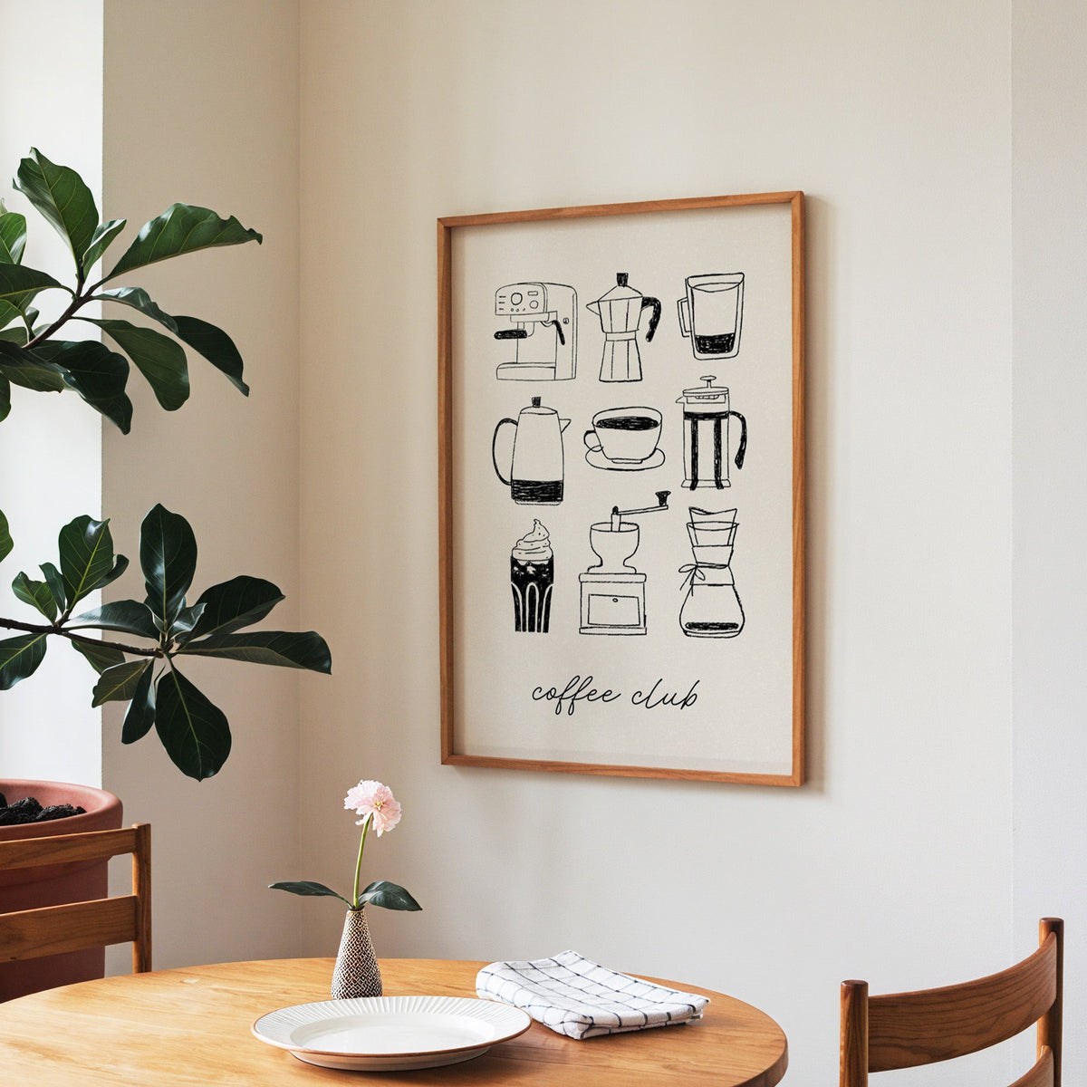 Coffee Club brewer grid print in a walnut frame above a round table beside a fiddle-leaf fig