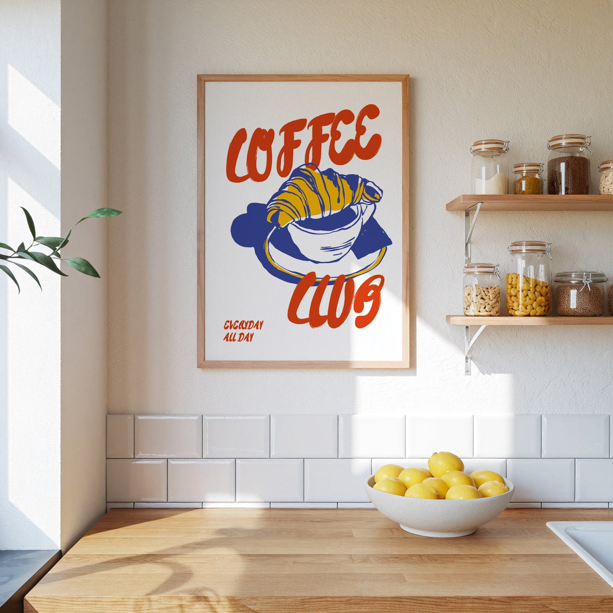 Coffee Club croissant print in an oak frame beside open kitchen shelves