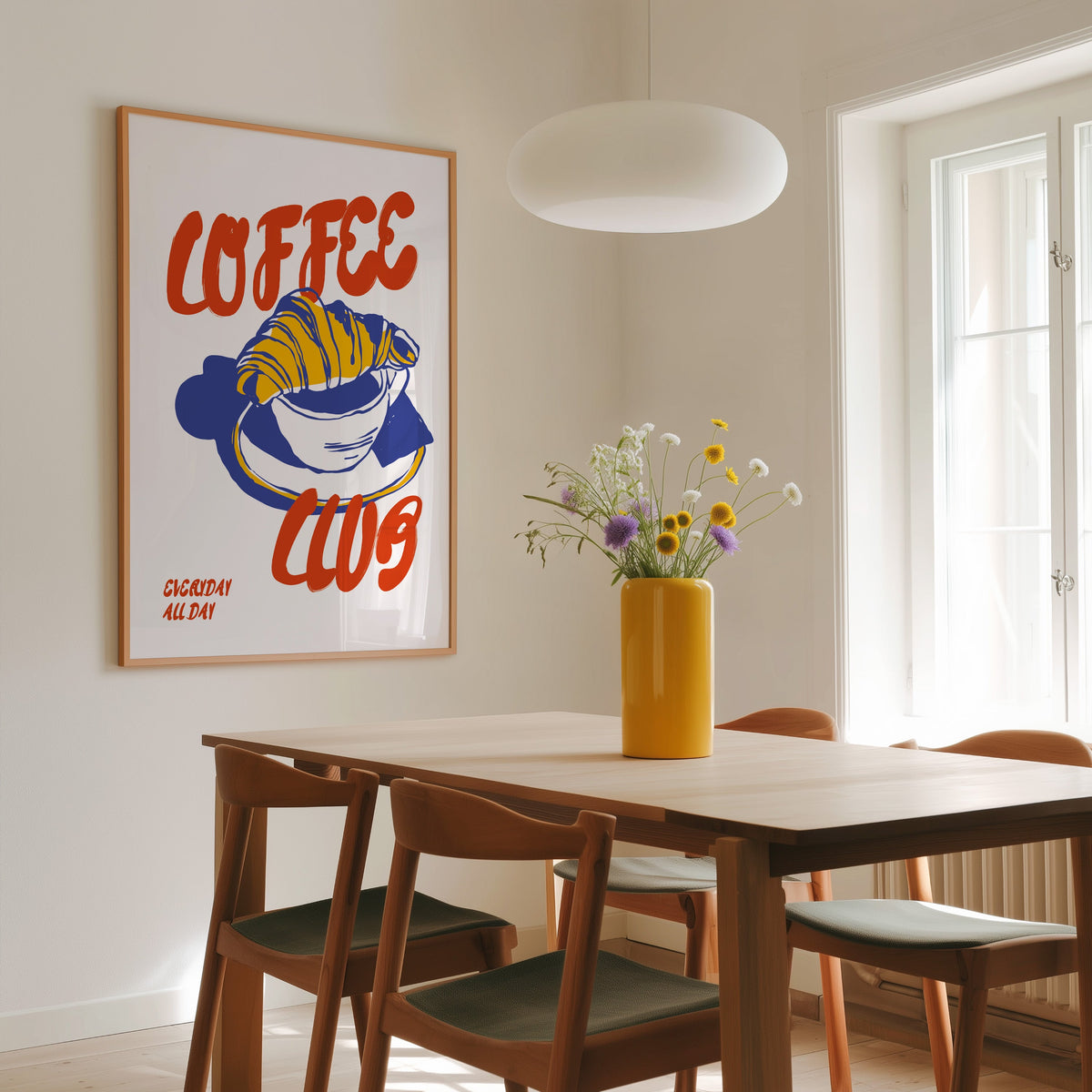 Coffee Club croissant print in a slim oak frame above a dining table