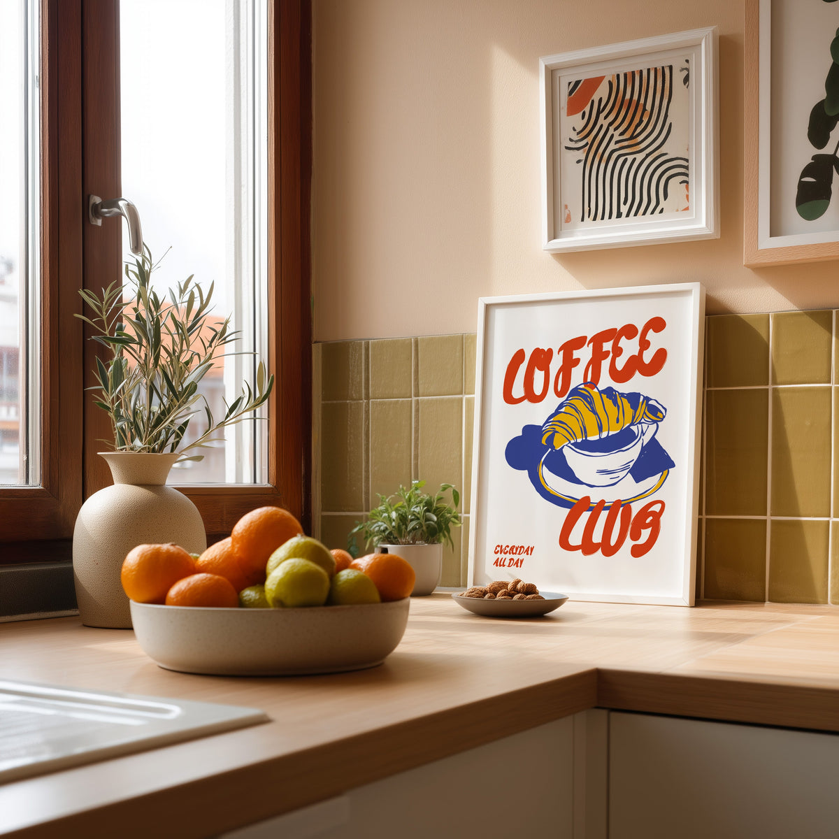 Coffee Club croissant print in a white frame against olive green kitchen tiles